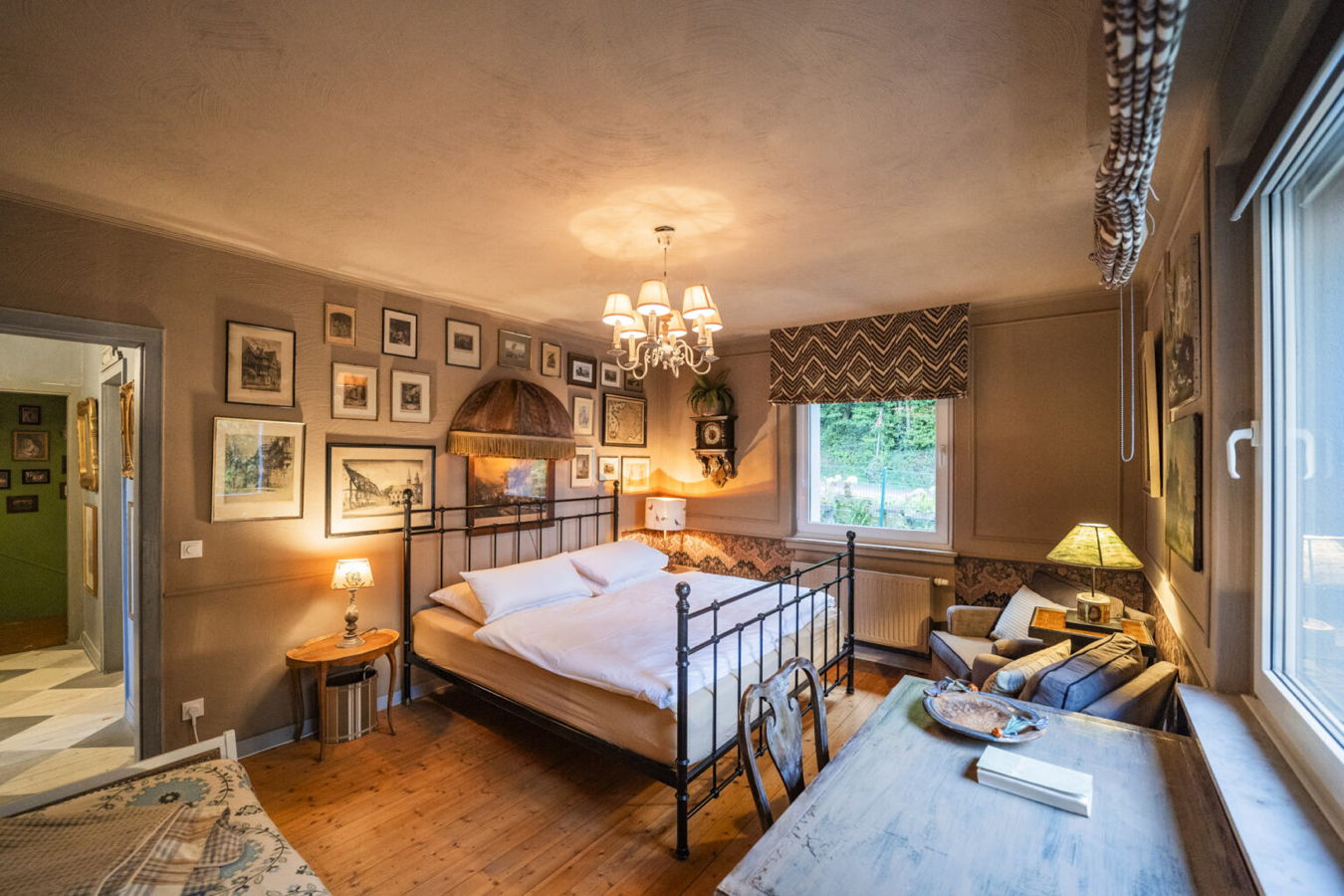 Restaurant, Hotel, Ferienhaus Gemütliches Schlafzimmer mit Metallbett, vielen gerahmten Bildern, Schreibtisch und Sitzbereich am Fenster