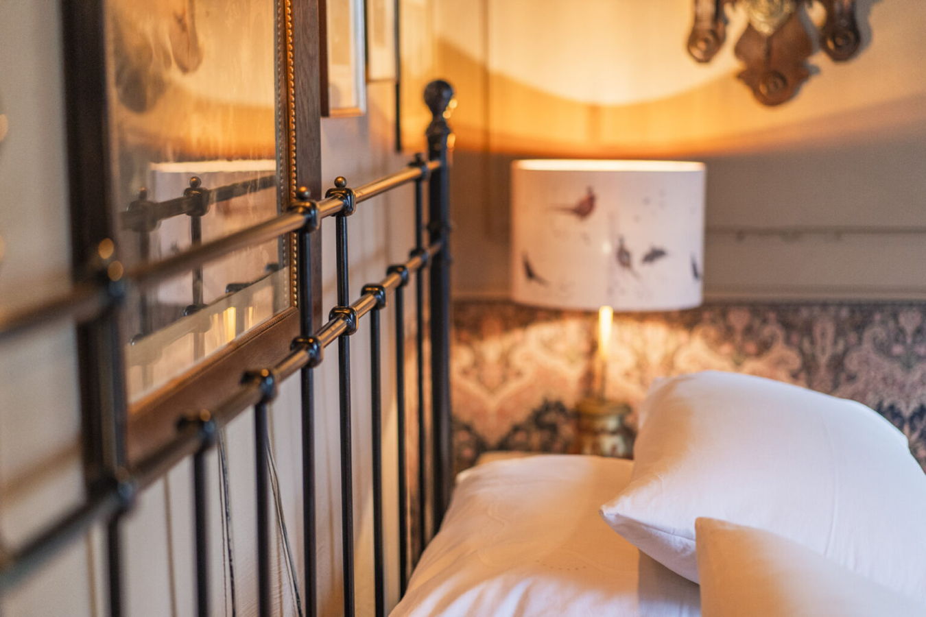Ein gemütlich beleuchtetes Bett mit weißer Bettwäsche und Nachttischlampe in einem Schlafzimmer