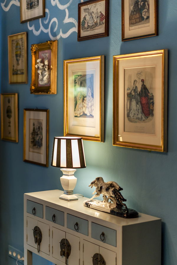 Dekorativ eingerichtete Wand mit gerahmten Bildern, Lampe und Pferdefigur