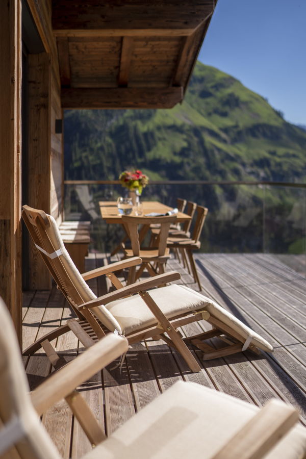 Holzterrasse mit Liegestühlen und Tisch vor Bergpanorama