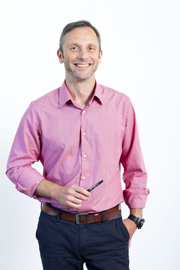 Lächelnder Mann in rosa Hemd mit Stift in der Hand
