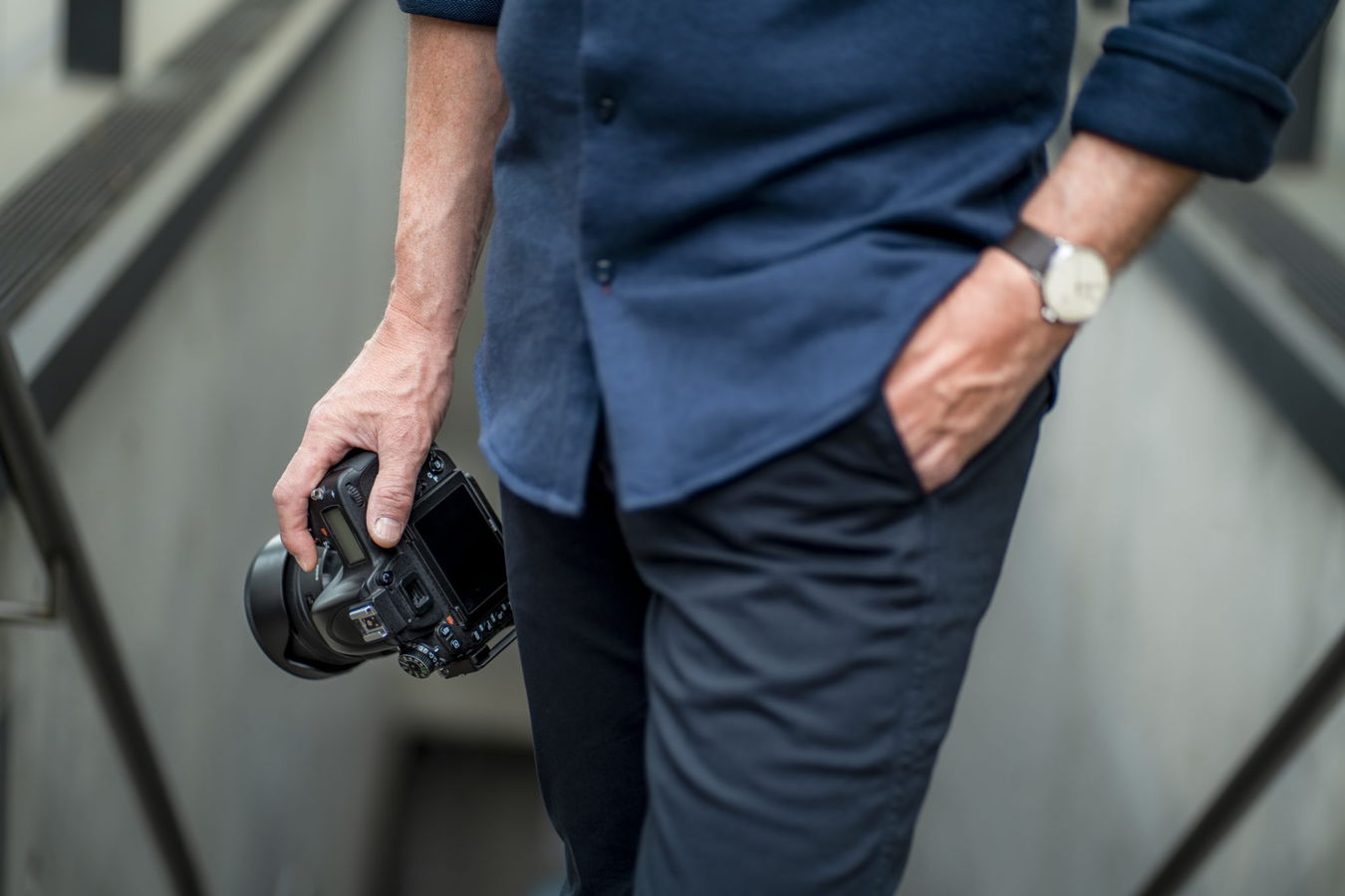 Mann hält eine Kamera in der Hand und steht auf einer Treppe