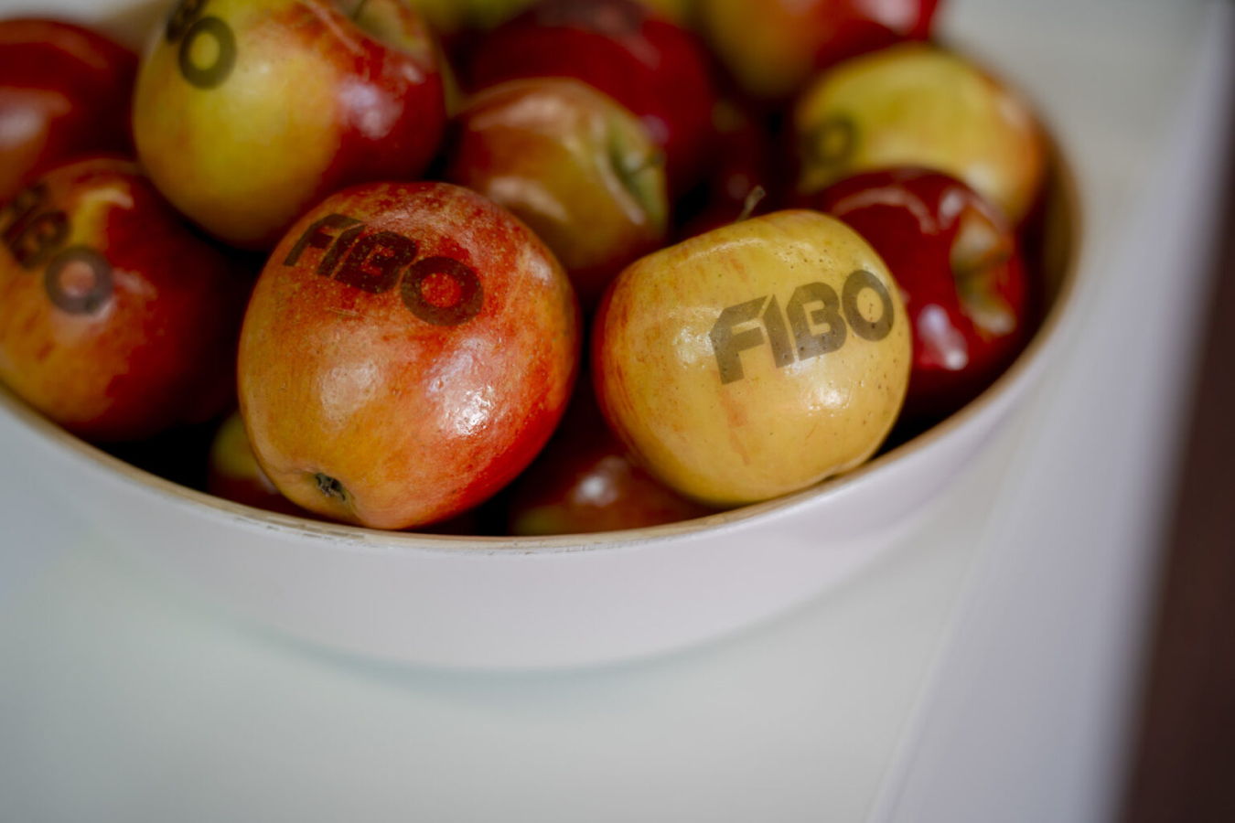 Äpfel mit dem Aufdruck „FIBO“ in einer Schale