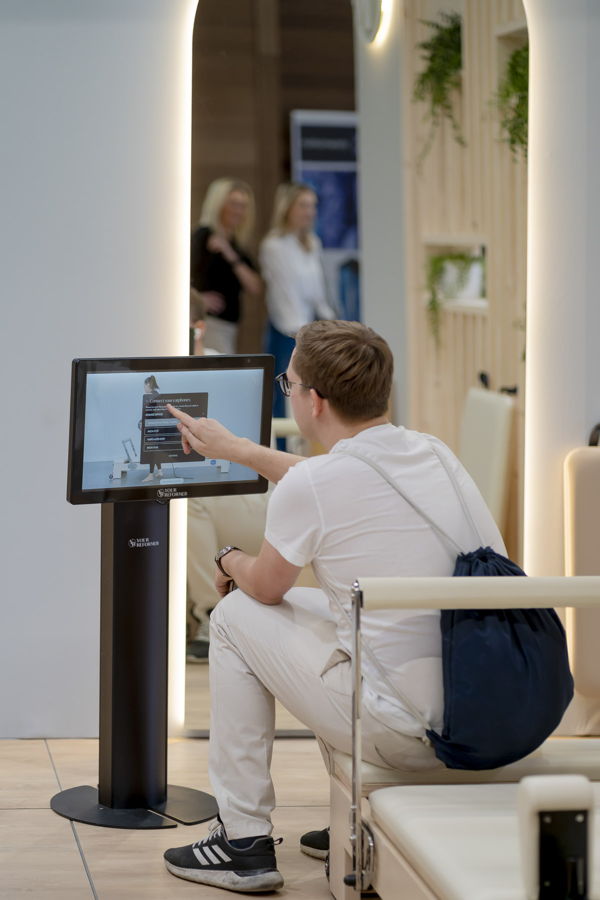 Mann bedient einen Touchscreen-Kiosk in einem hellen Ausstellungsraum