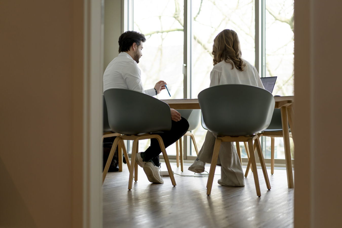 Zwei Personen sitzen an einem Tisch und besprechen etwas am Laptop
