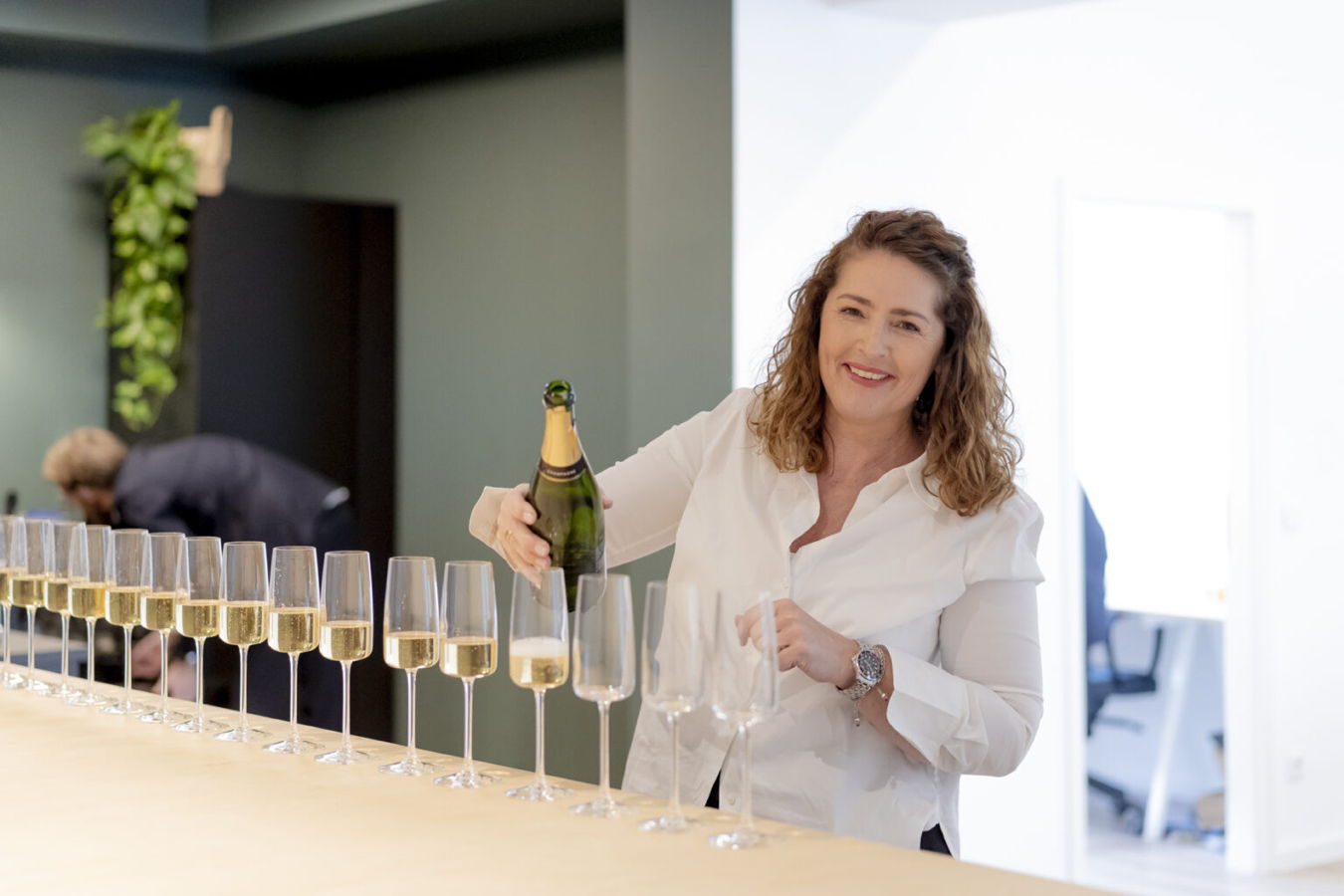 Frau schenkt Sekt in eine Reihe von Gläsern ein