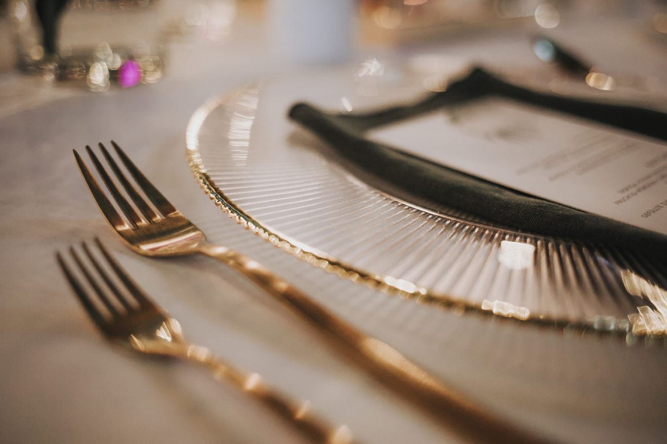 Festlich gedeckter Tisch mit goldenen Gabeln und Glasgeschirr