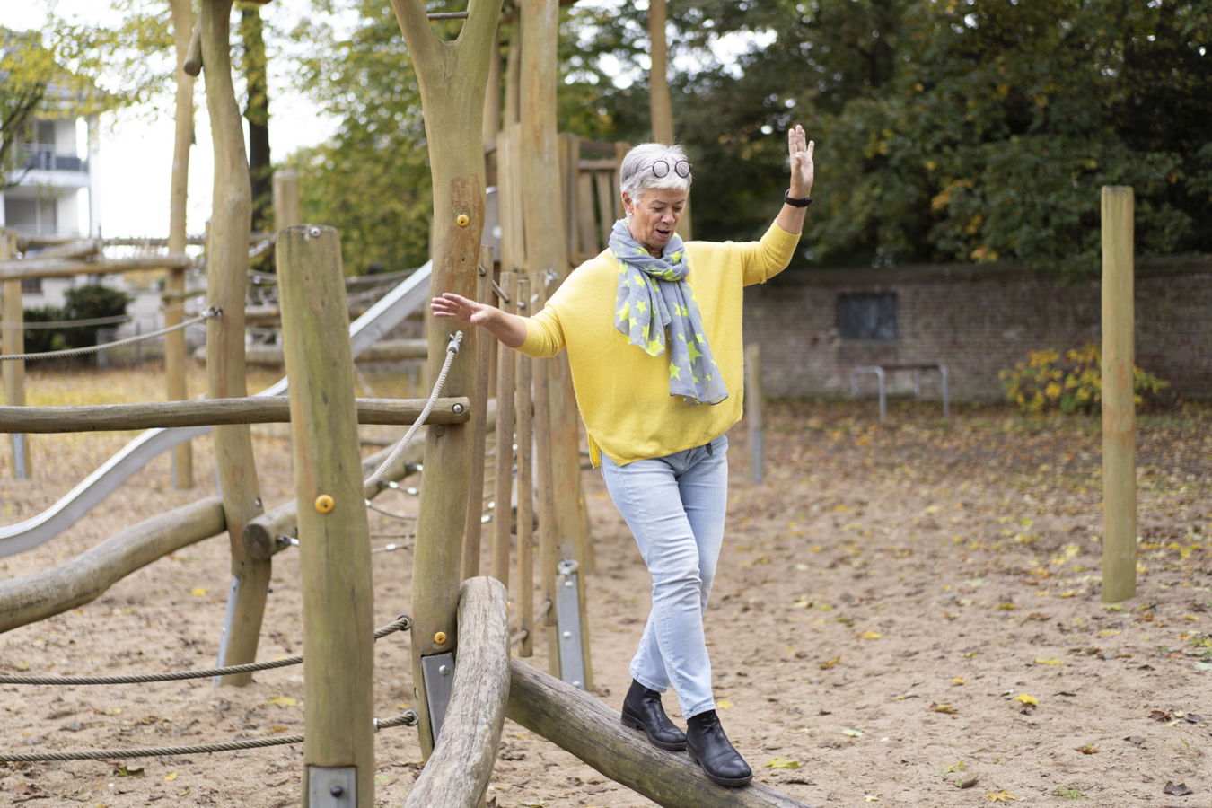 Ältere Frau balanciert auf einem Holzparcours im Freien