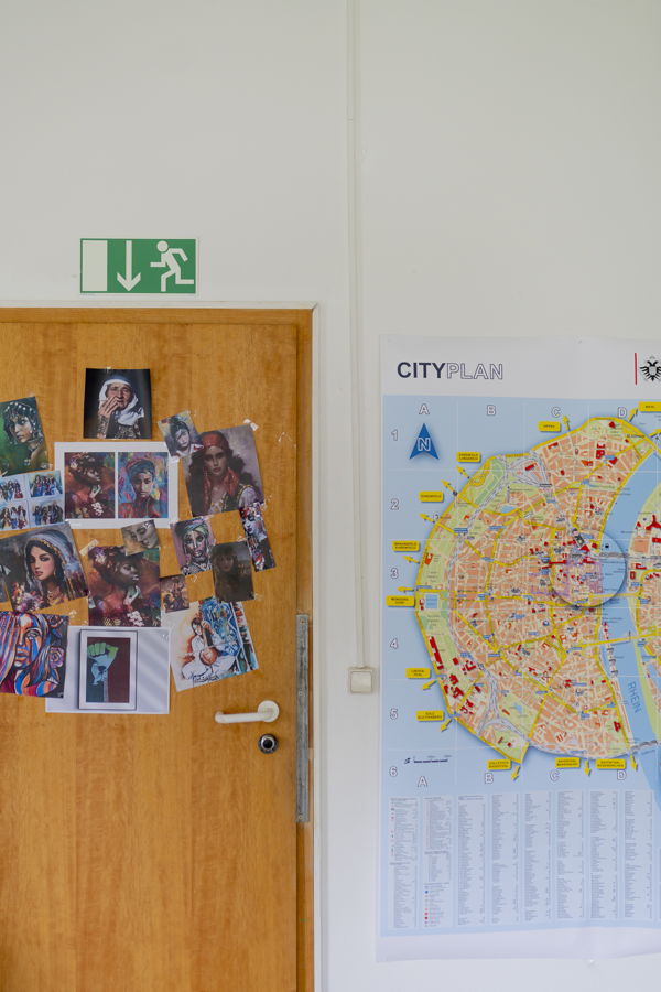 Holztür mit mehreren Kunstfotos; daneben hängt ein Stadtplan an der Wand