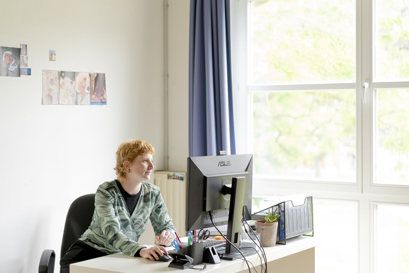 Frau arbeitet am Schreibtisch vor einem Computer in einem hellen Büro
