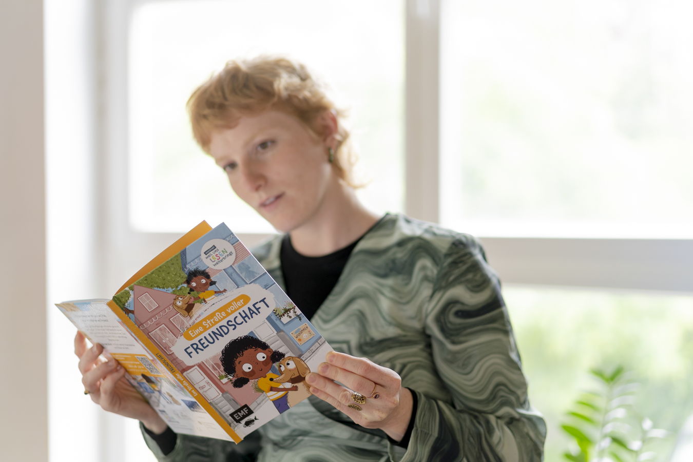 Frau liest ein Kinderbuch mit dem Titel „Eine Straße voller Freundschaft“