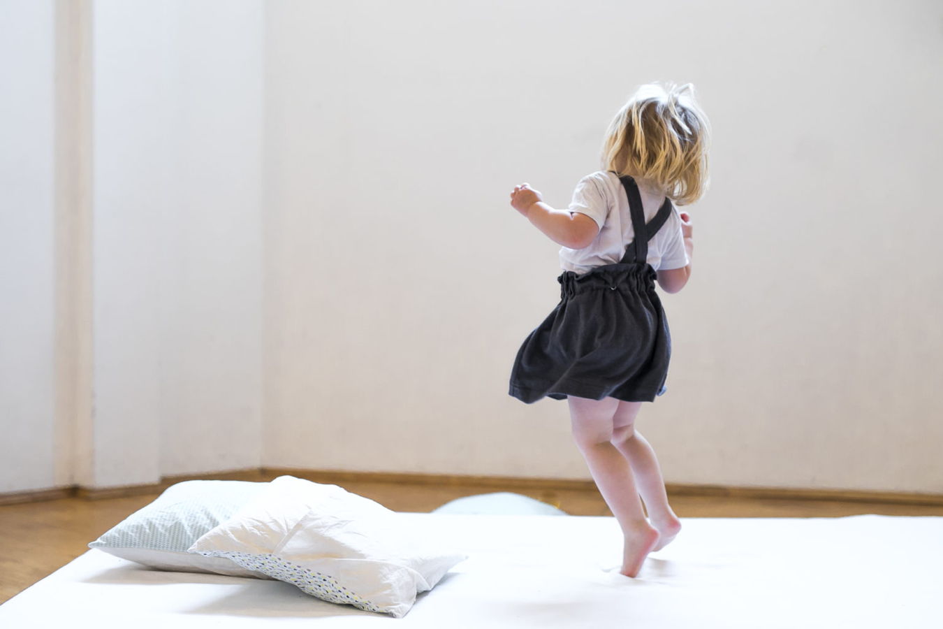 Kleinkind springt auf einer Matratze im Zimmer