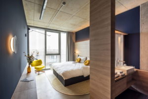 Modernes Schlafzimmer mit großem Fenster, Doppelbett und integriertem Badbereich