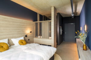 Modernes Hotelzimmer mit Doppelbett, Holzverkleidung und dunklen Wänden