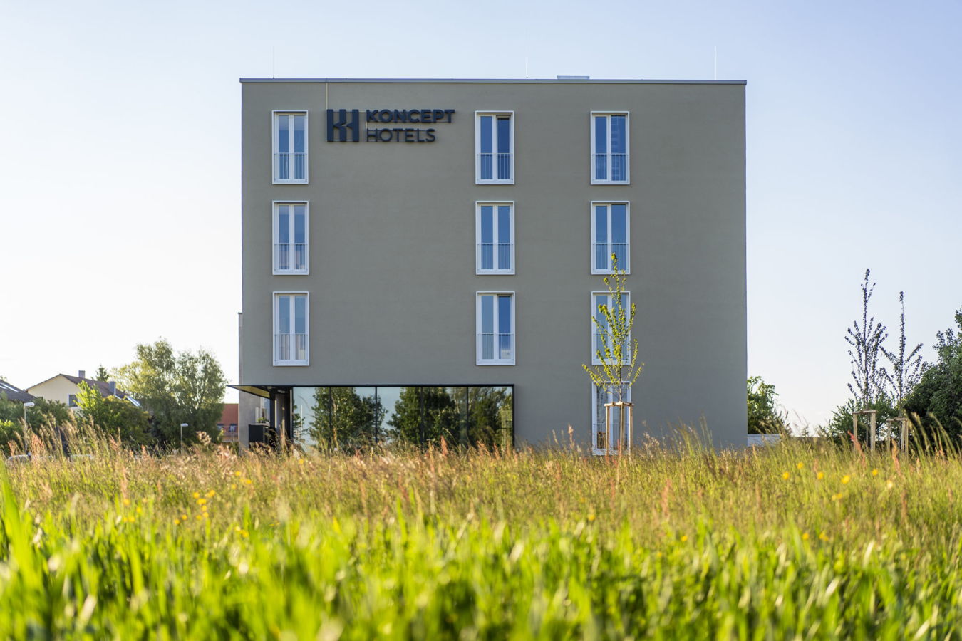 Restaurant, Hotel, Ferienhaus Konzept-Hotels-Gebäude hinter einer Wiese mit jungen Bäumen