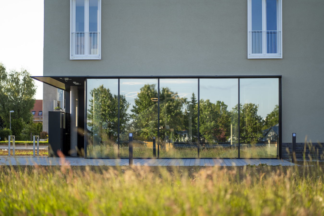 Glasfront eines modernen Gebäudes mit Eingang und Spiegelung von Bäumen