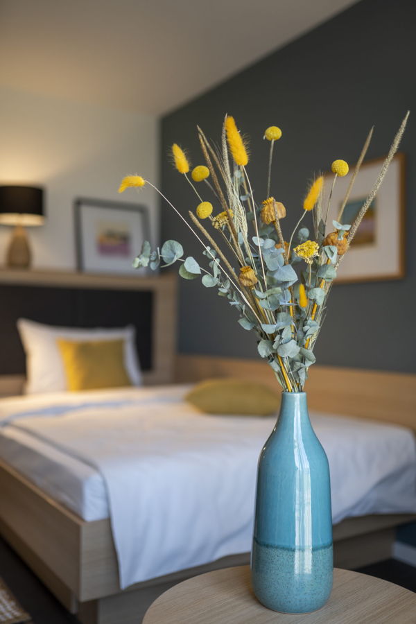 Türkise Vase mit Trockenblumen auf einem Tisch im Schlafzimmer