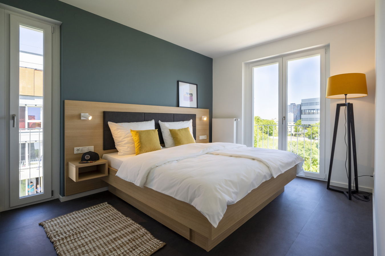Modernes Schlafzimmer mit Doppelbett, großen Fenstern und Stehlampe