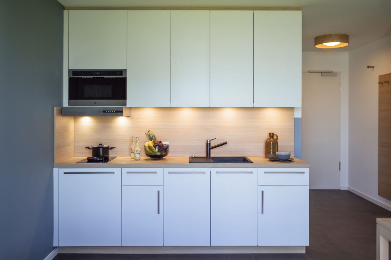 Moderne Küche mit weißen Schränken, Kochfeld, Spüle und Einbauofen