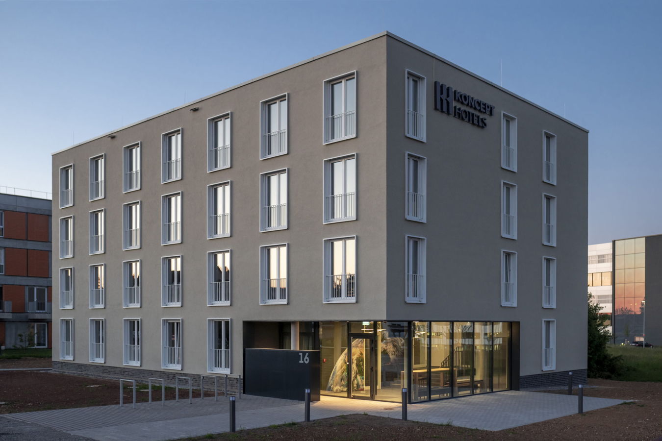 Hotelgebäude von Koncept Hotels mit verglastem Eingang bei Dämmerung