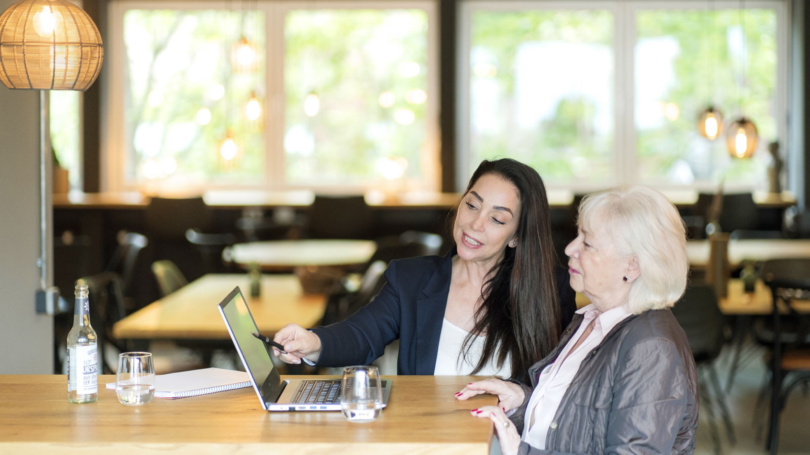 Zwei Frauen besprechen etwas an einem Laptop in einem Café