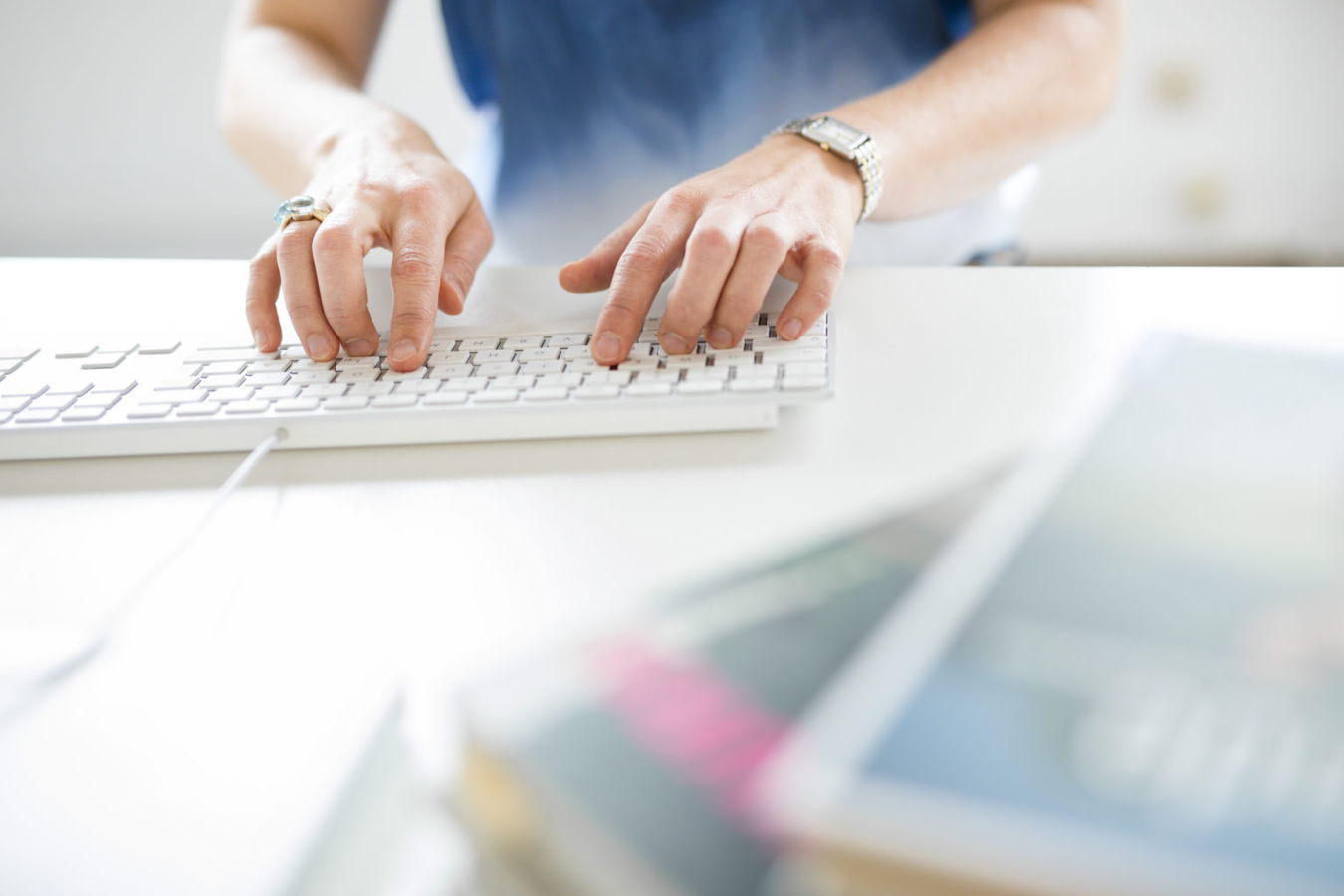 Hände tippen auf einer weißen Tastatur