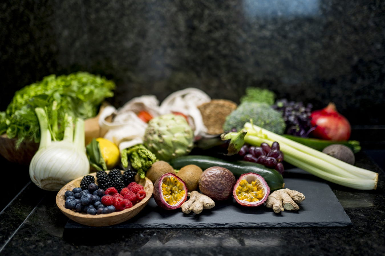 Eine Auswahl frischer Obst- und Gemüsesorten, darunter Beeren, Fenchel, Sellerie, Ingwer und Passionsfrucht