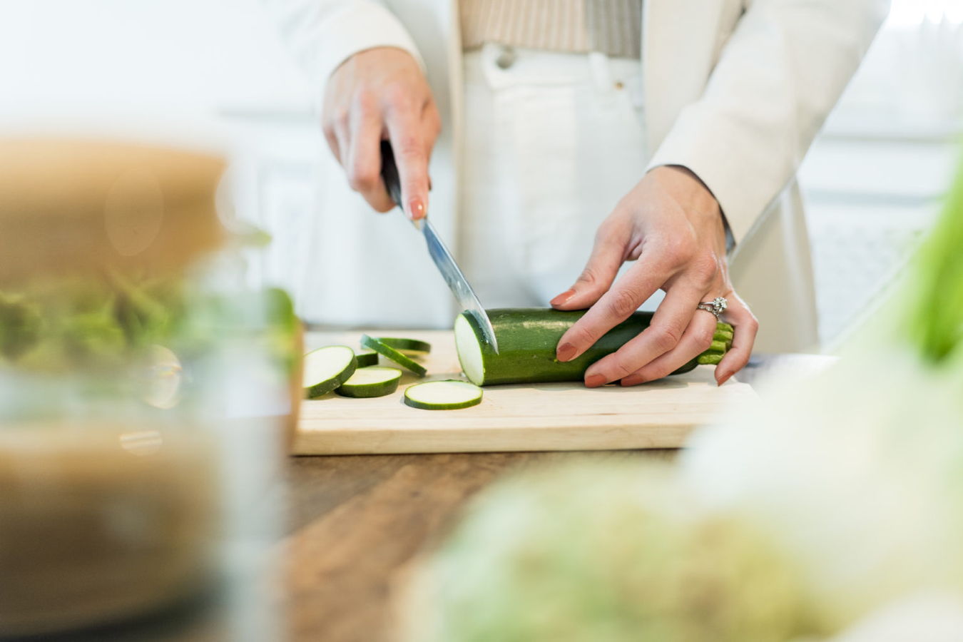 Eine Person schneidet eine Zucchini auf einem Schneidebrett in Scheiben