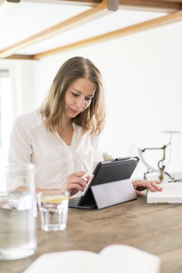 Frau arbeitet an einem Tablet am Tisch