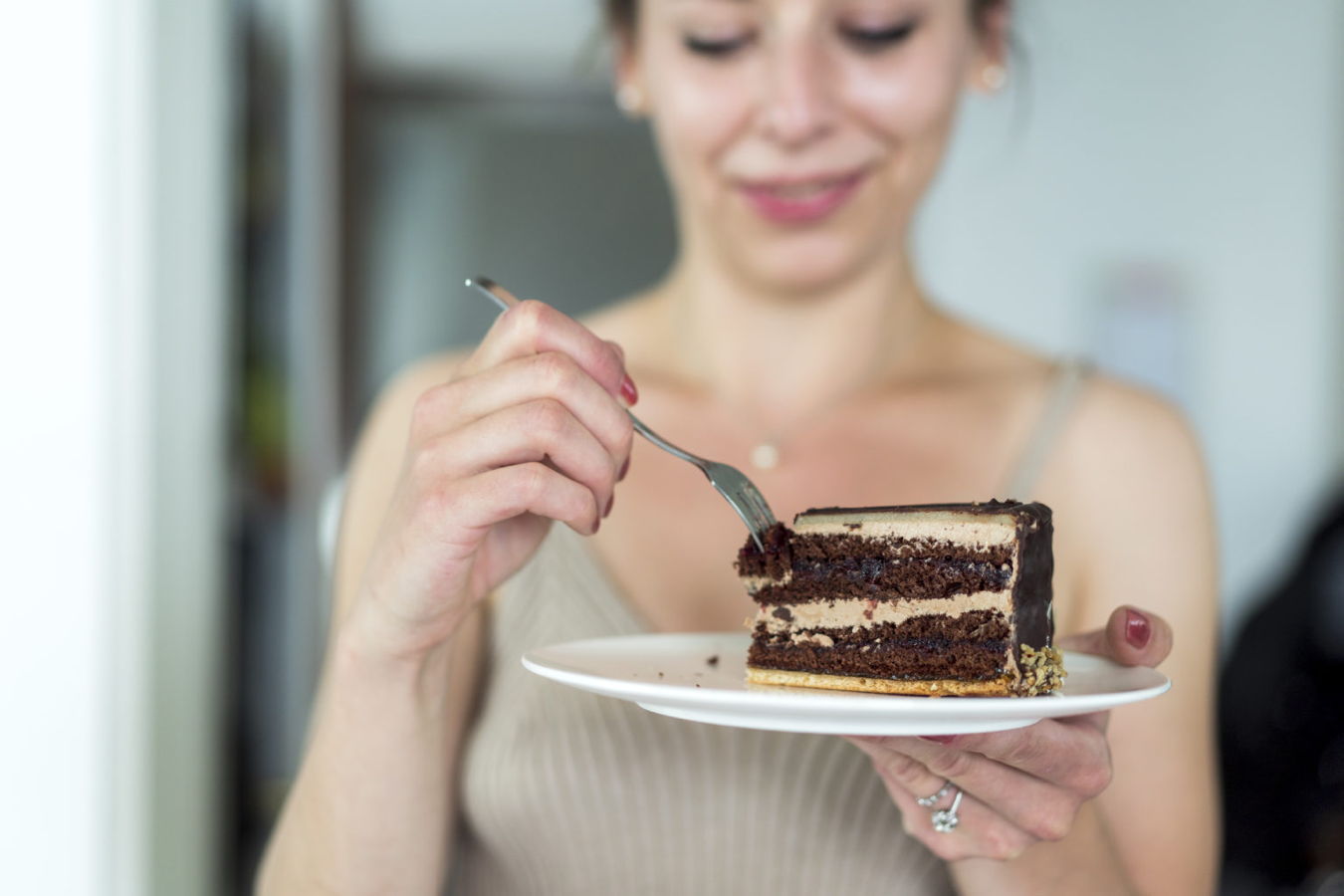 Frau isst ein Stück Schokoladenkuchen von einem Teller mit einer Gabel