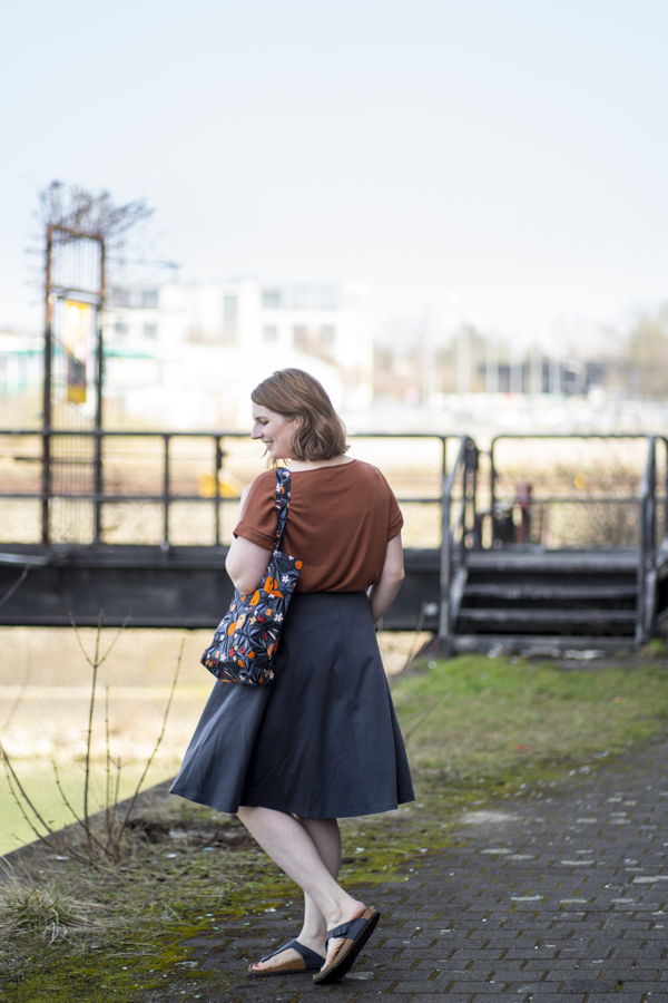 Eine Frau steht draußen am Wasser und blickt über die Schulter zurück