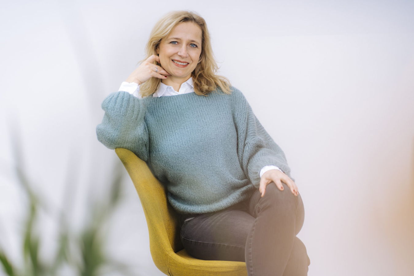 Frau sitzt lächelnd auf einem gelben Stuhl