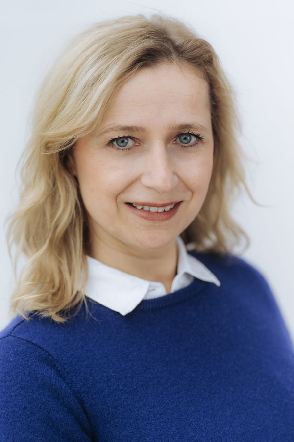 Porträt einer lächelnden blonden Frau in blauem Pullover und weißem Kragen