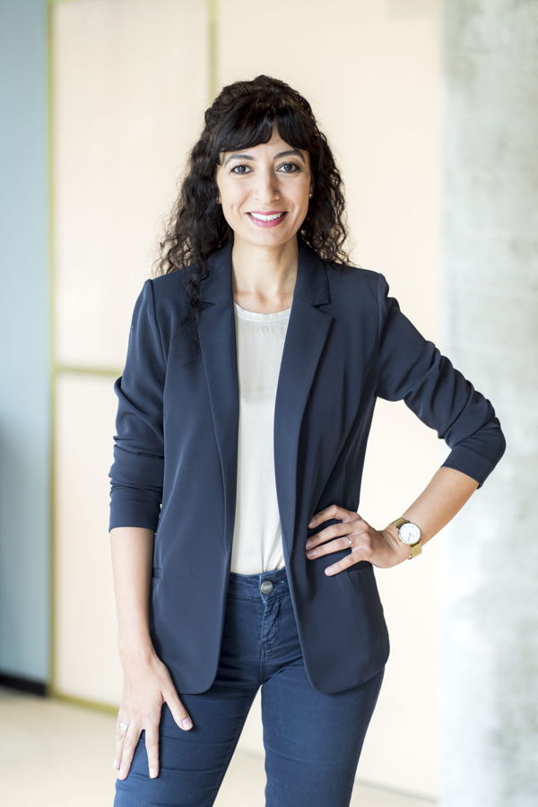 Porträt einer lächelnden Frau in Blazer und Jeans, die selbstbewusst steht
