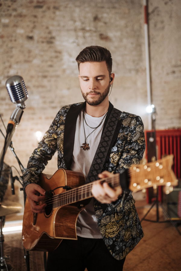 Ein Mann spielt Akustikgitarre vor einem Mikrofon in einem Musikstudio