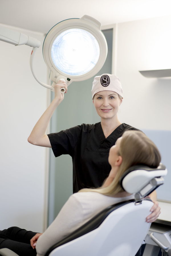 Zahnärztin bei der Behandlung einer Patientin im Behandlungsstuhl