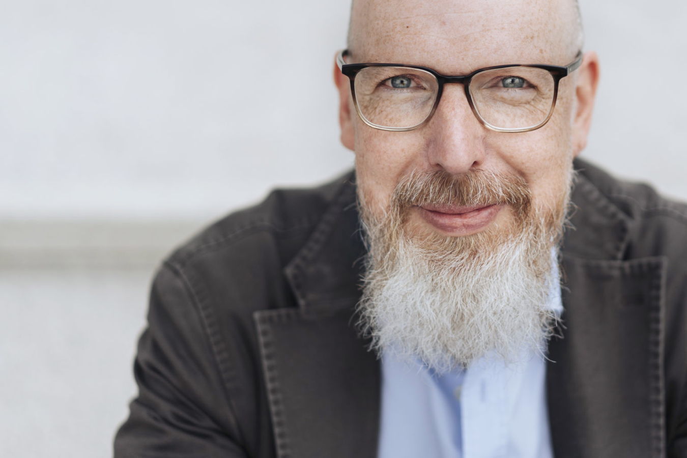 Porträt eines bärtigen Mannes mit Brille, der in die Kamera blickt