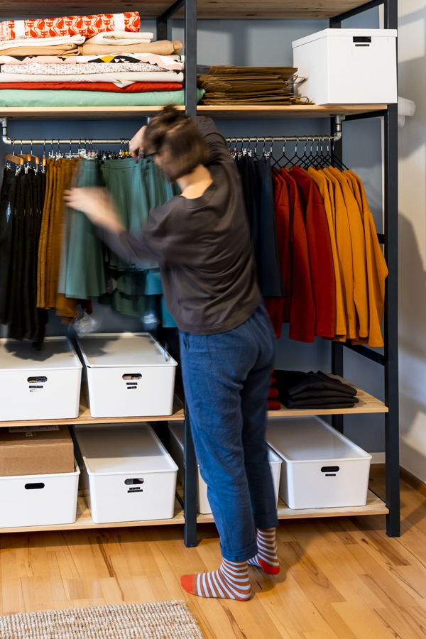 Eine Person ordnet Kleidung in einem offenen Kleiderschrank