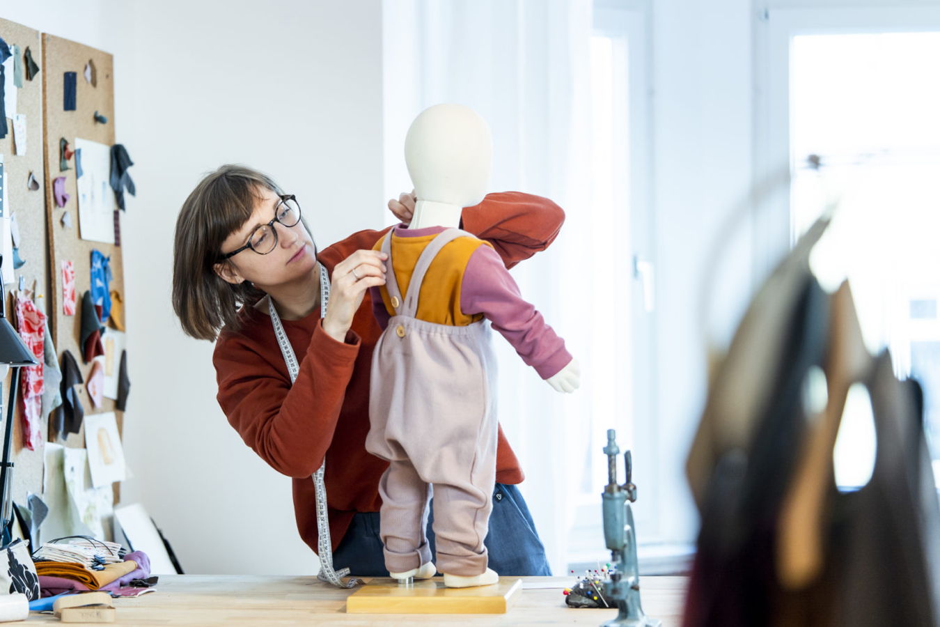 Schneiderin passt ein Kinderkleid an einer Schaufensterpuppe an