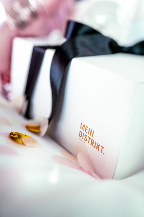 Geschenkbox mit schwarzer Schleife und Aufdruck „MEIN DISTRIKT.“