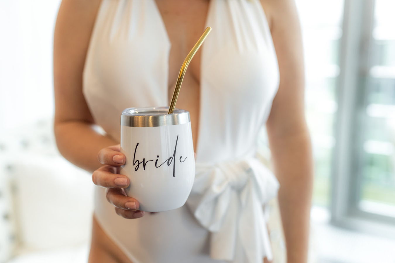 Braut hält einen Becher mit der Aufschrift „bride“ und einem goldenen Strohhalm