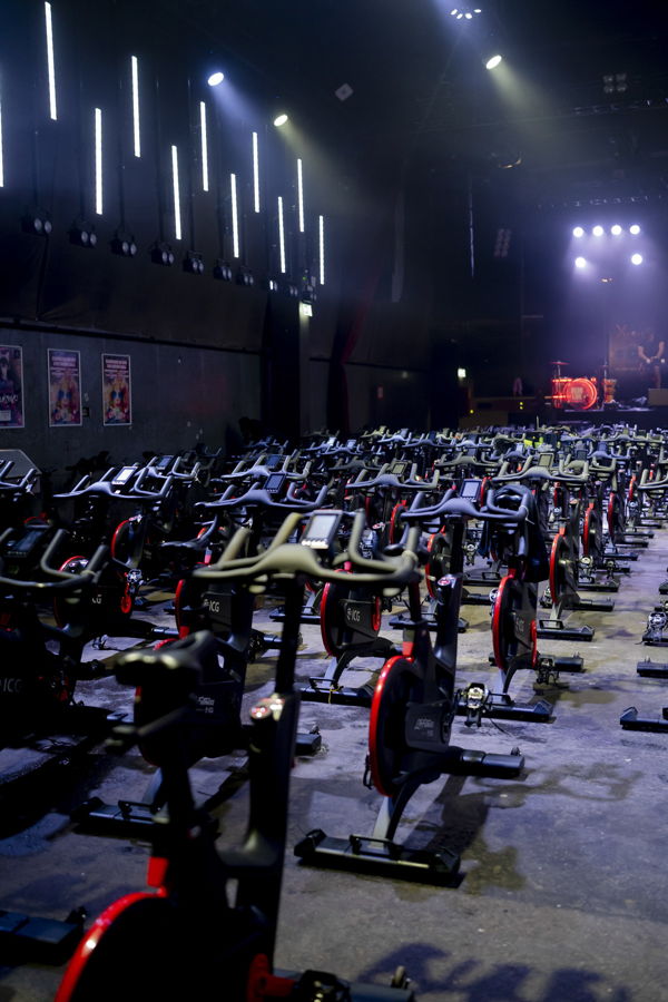 Fitnessstudio mit vielen Spinningrädern vor einer Bühne mit Beleuchtung