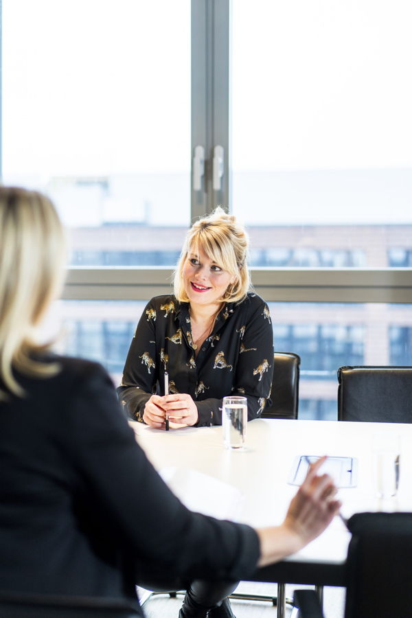 Zwei Frauen führen ein Gespräch an einem Konferenztisch im Büro