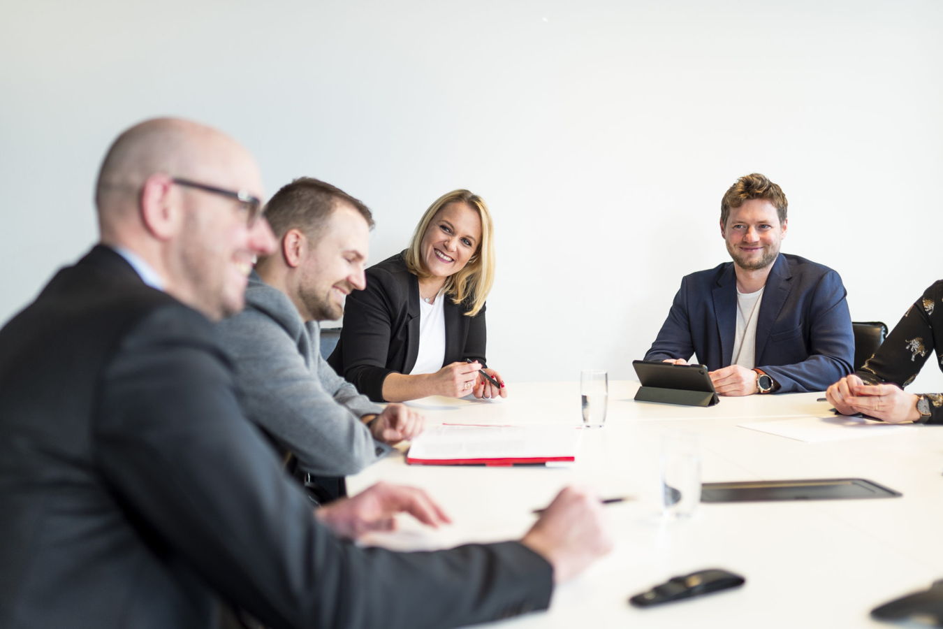 Mehrere Personen sitzen an einem Konferenztisch und besprechen sich in einem Meeting