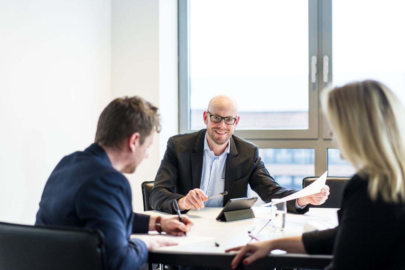 Drei Personen besprechen Unterlagen in einem Besprechungsraum