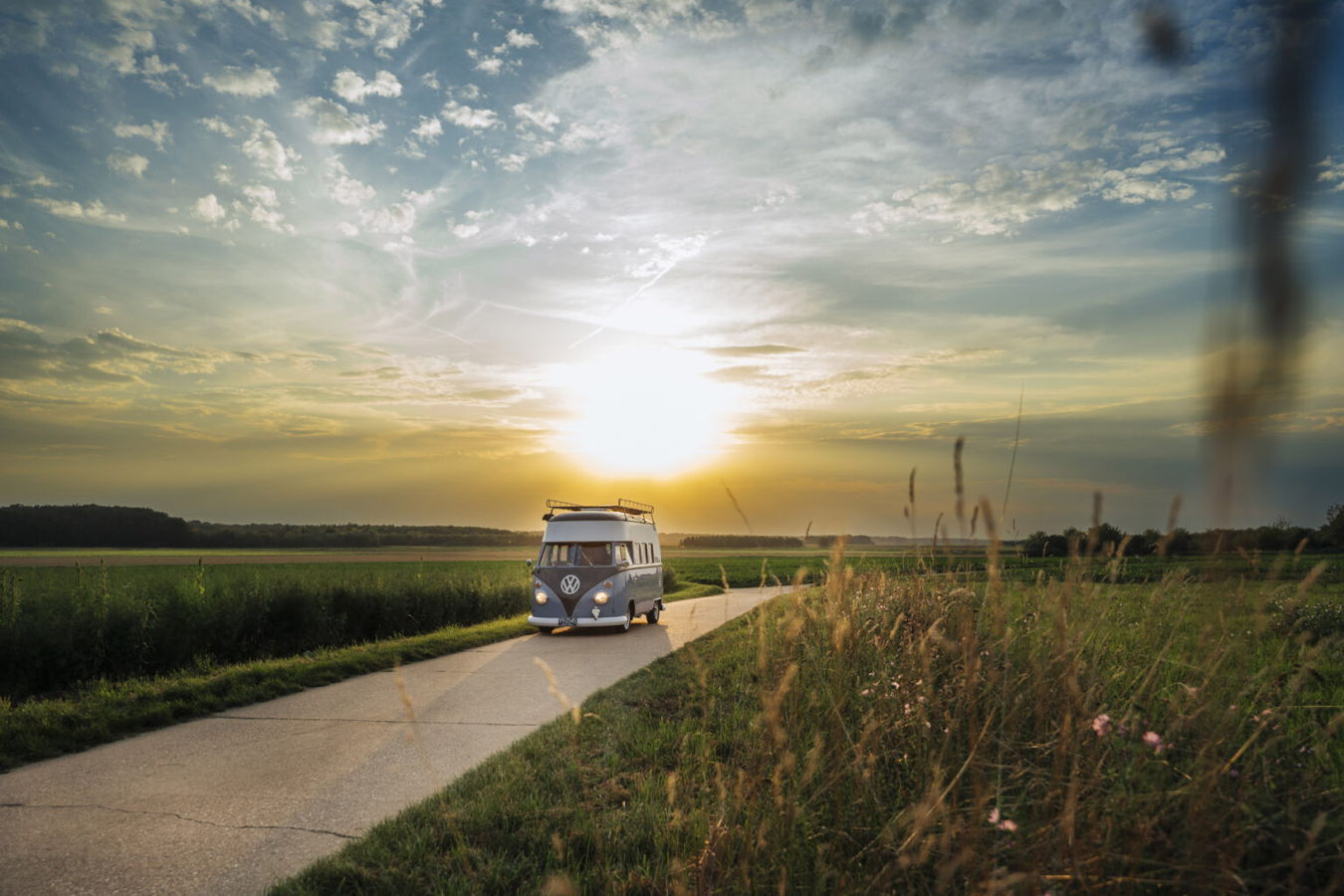 VW-Bus auf einer Landstraße bei Sonnenuntergang