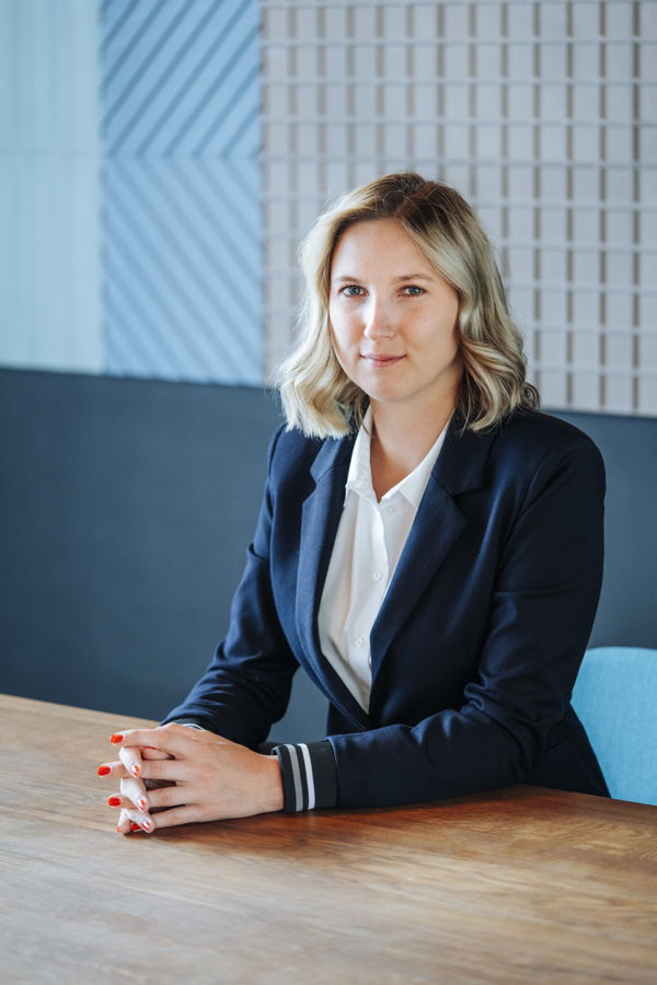 Porträt einer Frau im Business-Outfit, die an einem Tisch sitzt