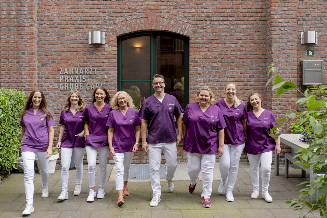 Team der Zahnarztpraxis Grube-Gard vor dem Eingang der Praxis