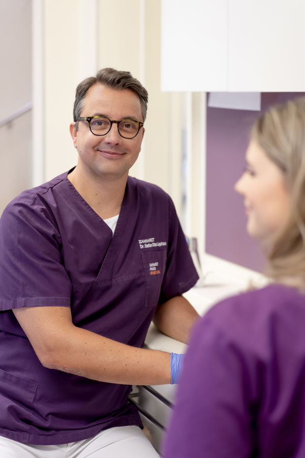 Zahnarzt im Gespräch mit einer Patientin in der Praxis