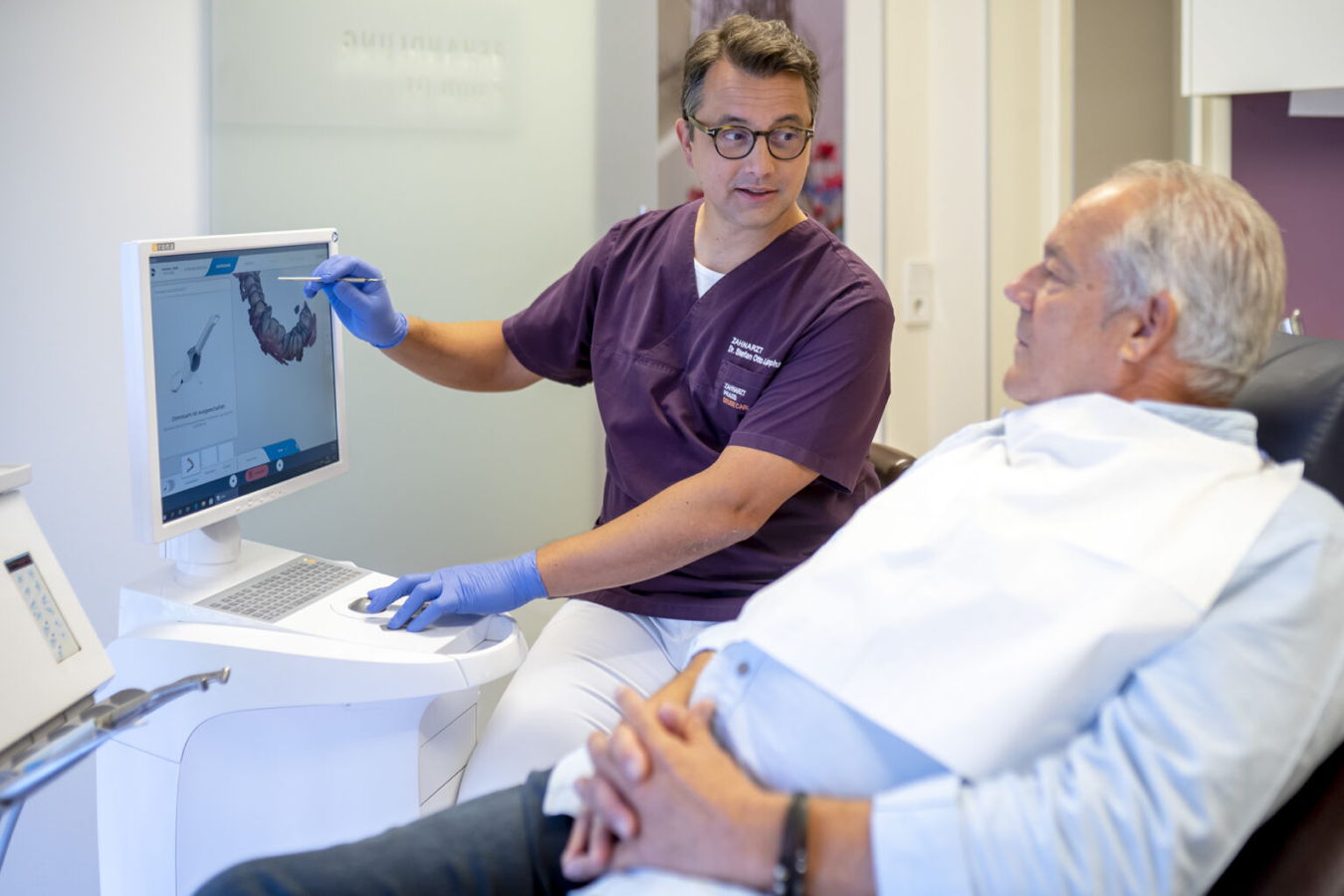 Zahnarzt erklärt einem Patienten eine Behandlung am Bildschirm